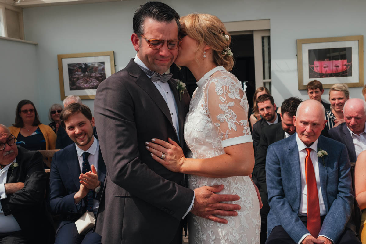 an woman kisses her emotional groom