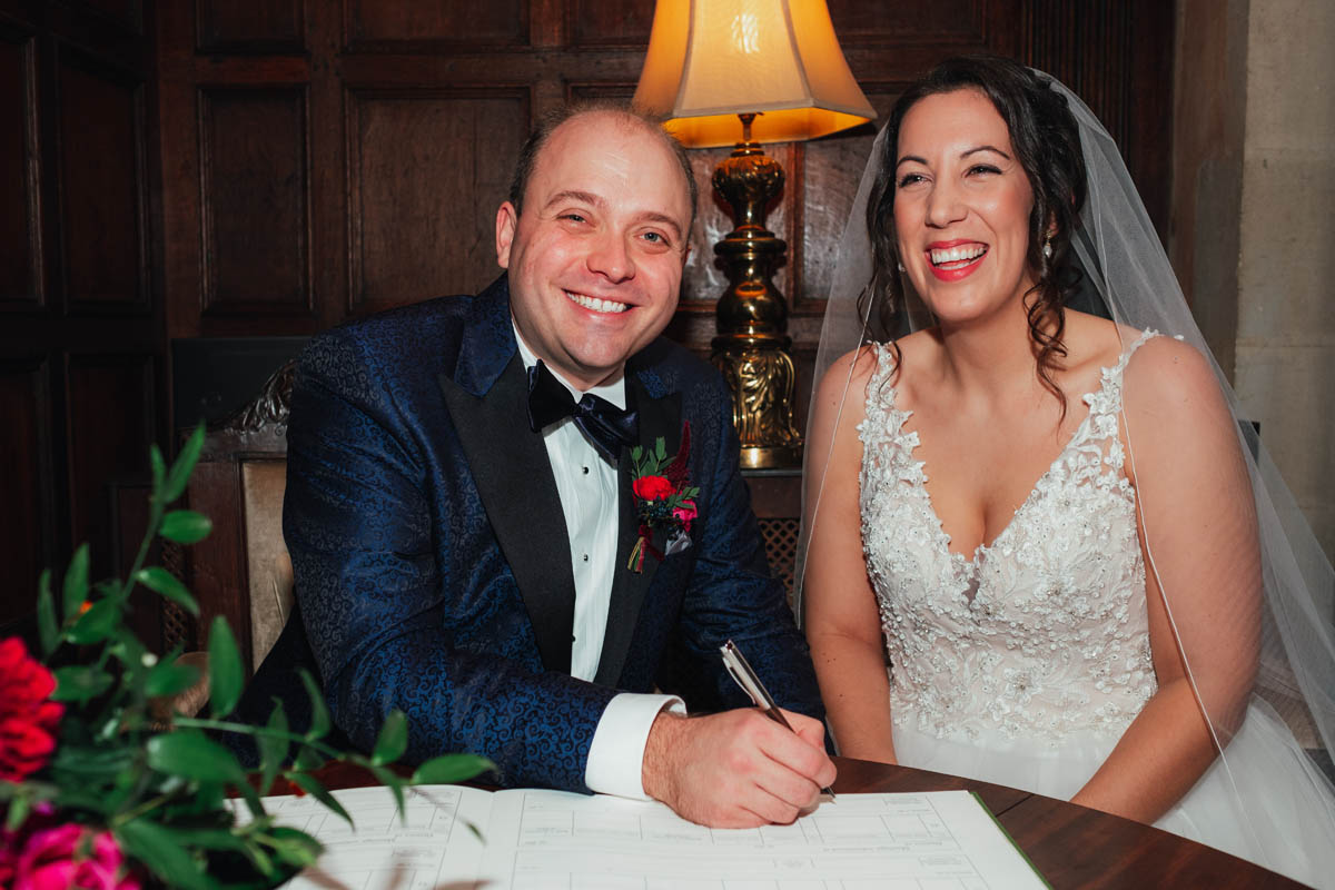 the newly weds smile as they sign the register