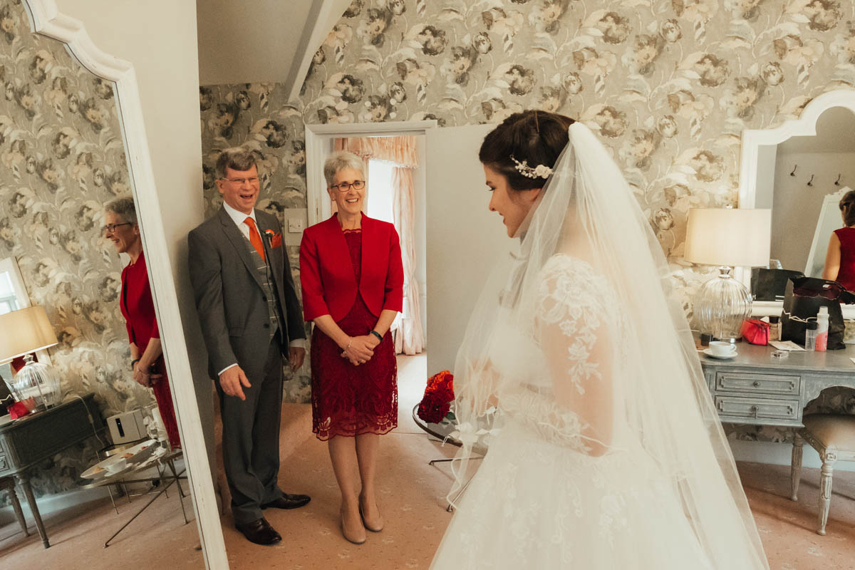 the bride's parents look delighted to see her