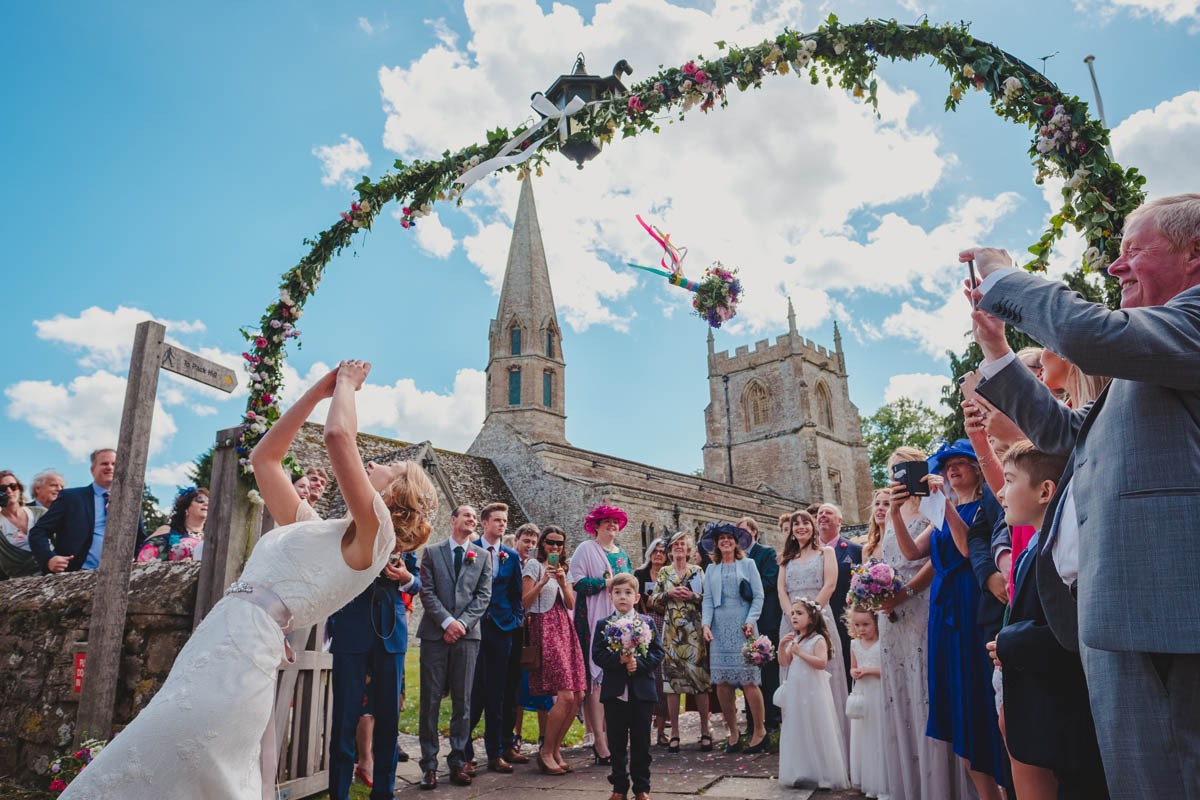 a bride throws her bouquet while guests eagerly wait to catch it