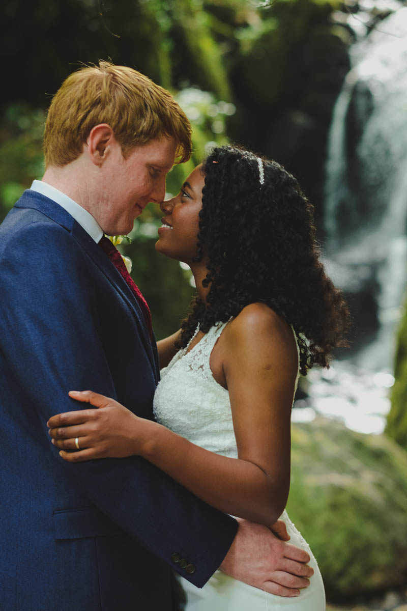 happy newlyweds having a kiss in front of canonteign falls