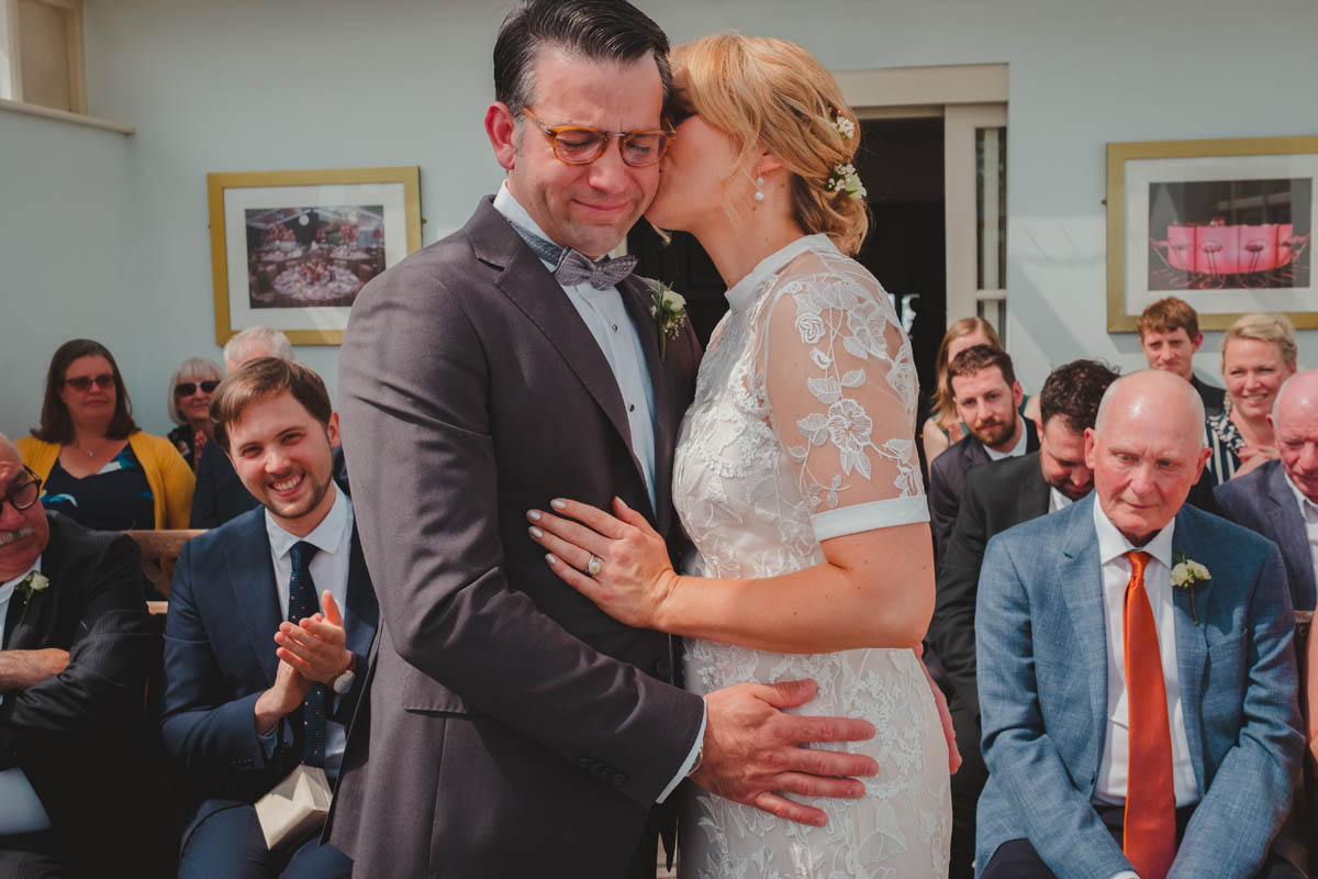 wife kisses her new groom who is crying