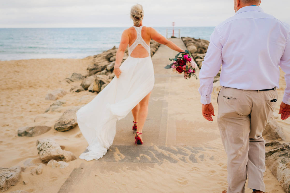 bride and groom running along the beach at their wedding in Dorset