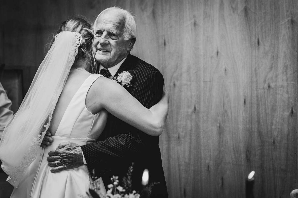 the bride's grandfather gives her an emotional hug