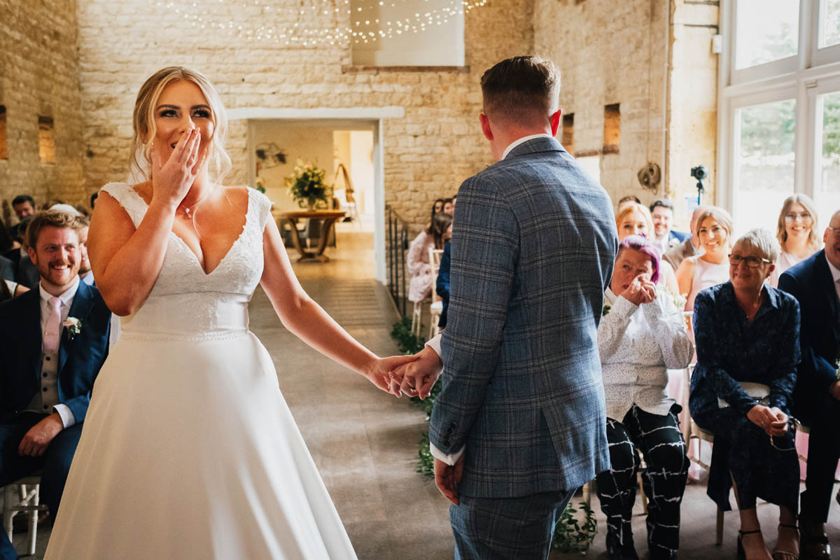 bride looks delighted to see her husband to be at capstone barn in the Cotswolds