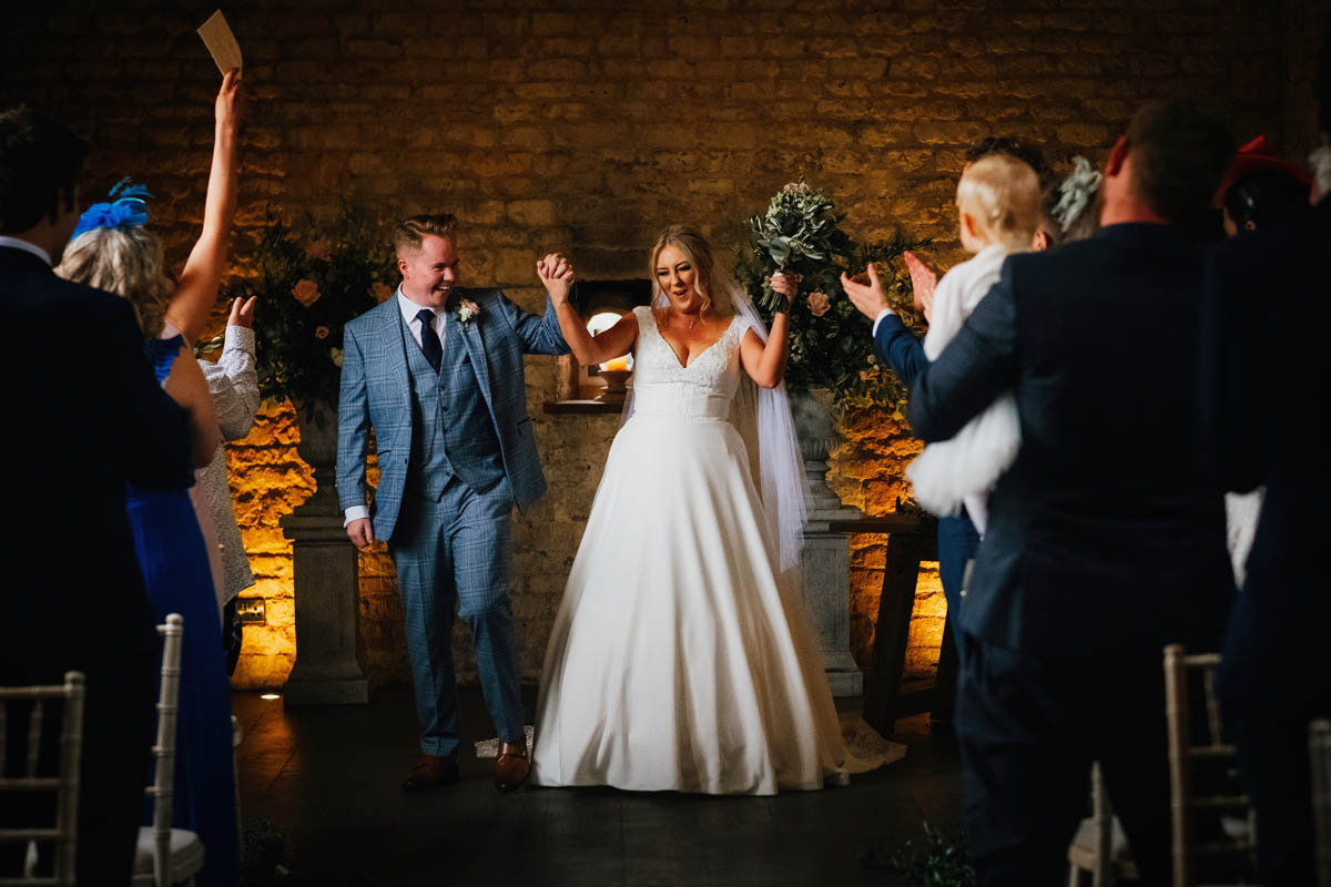 bride and groom throw their arms in the air in joy having just been pronounced husband and wife