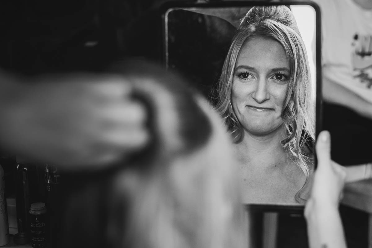 the bride smiling into the mirror in black and white
