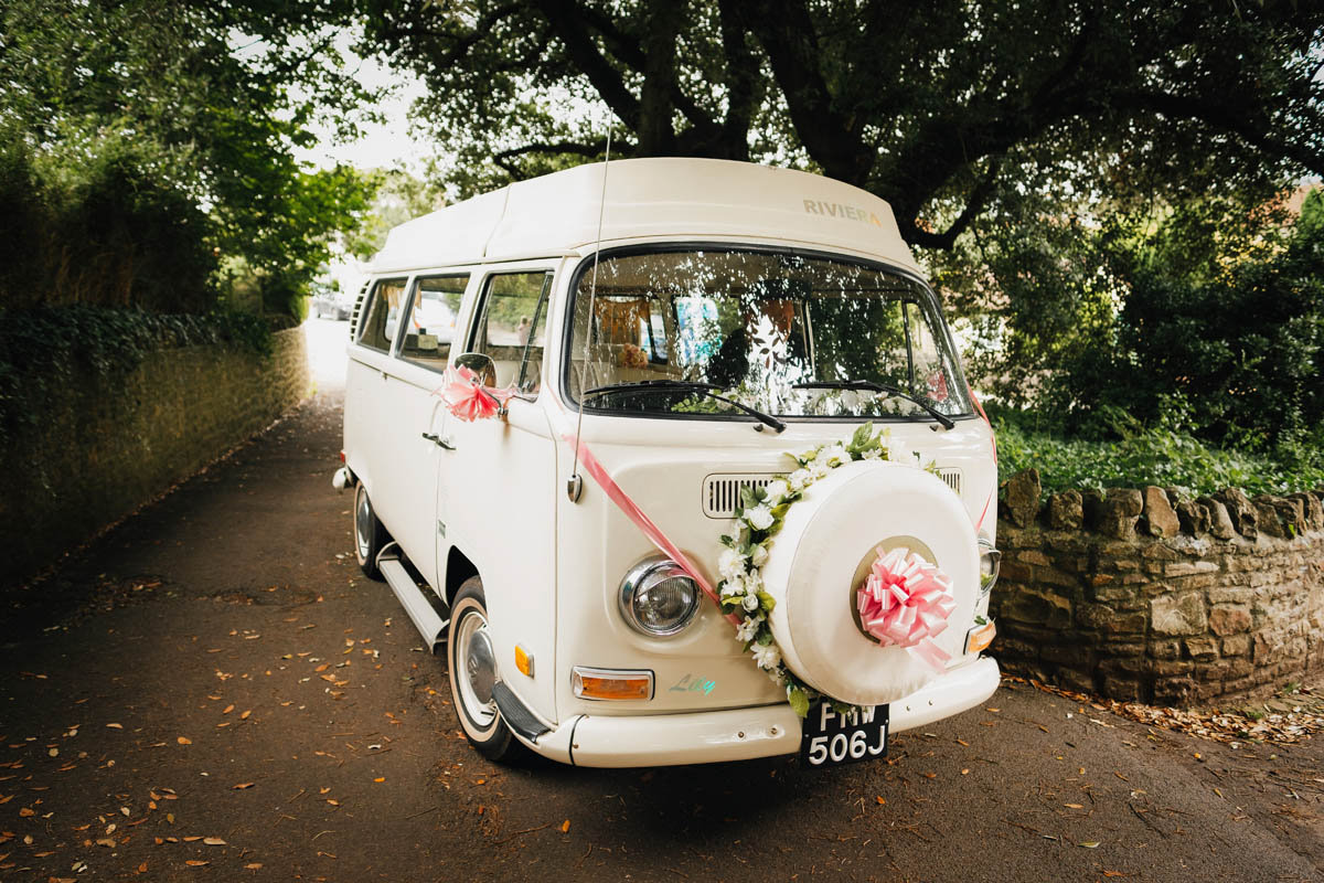 the wedding car, a VW camper adorned with flowers and ribbons