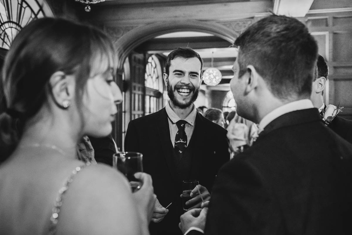 black and white image of wedding guests smiling during the drinks reception