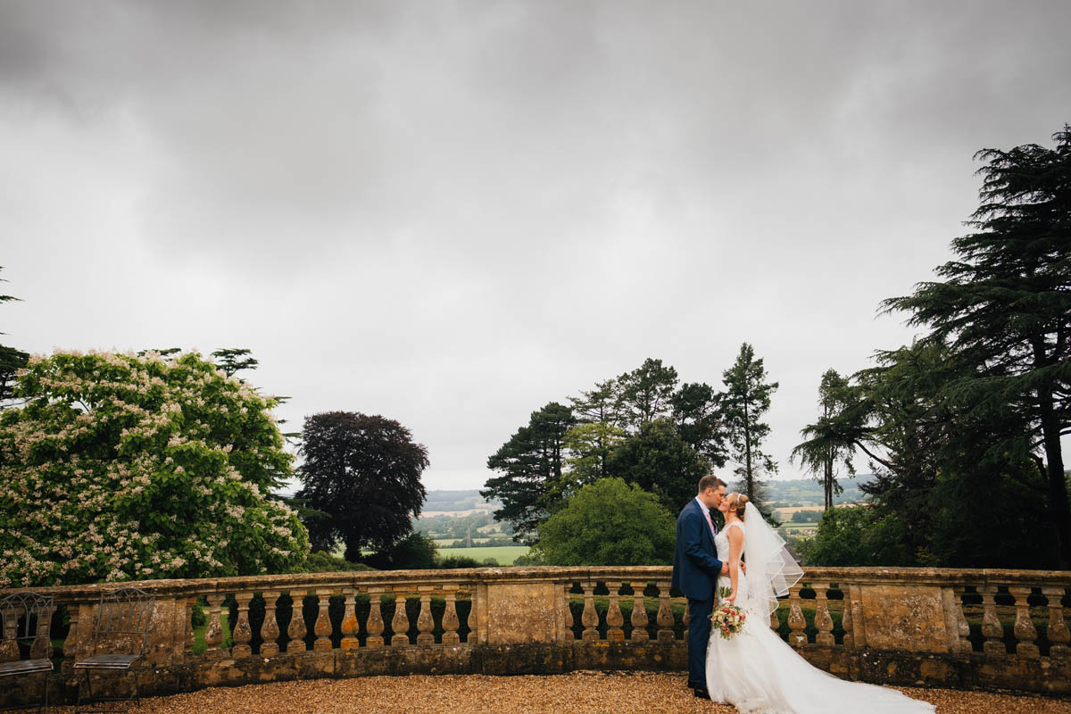 the couple kiss in the gardens with North Somerset countryside behind