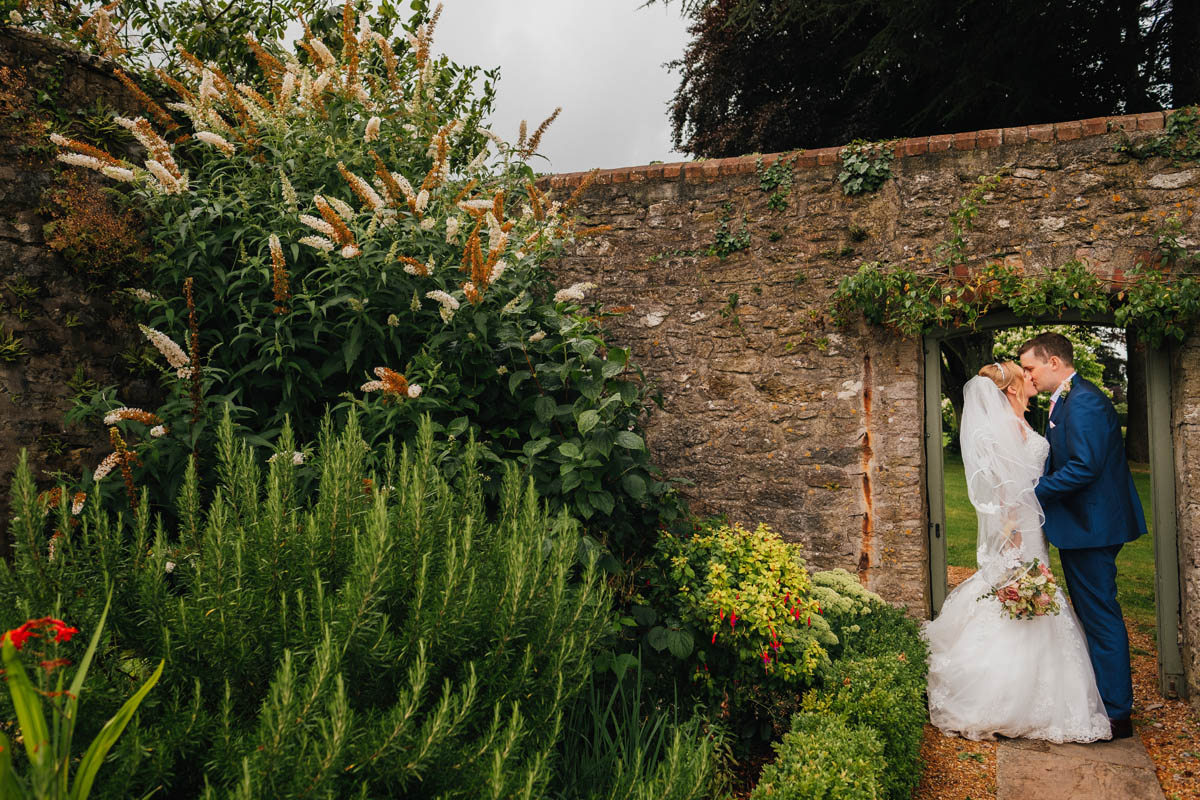 the bride and groom kiss in the walled garden at Coombe lodge