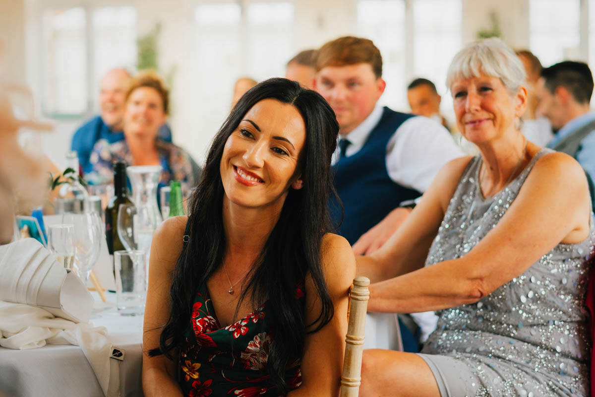 wedding guests smile as they listen to the best man speech