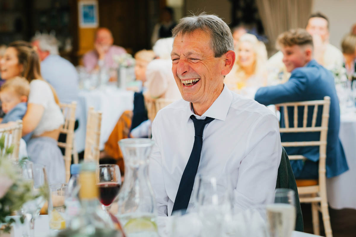 a wedding guest laughs at the father of the bride's speech