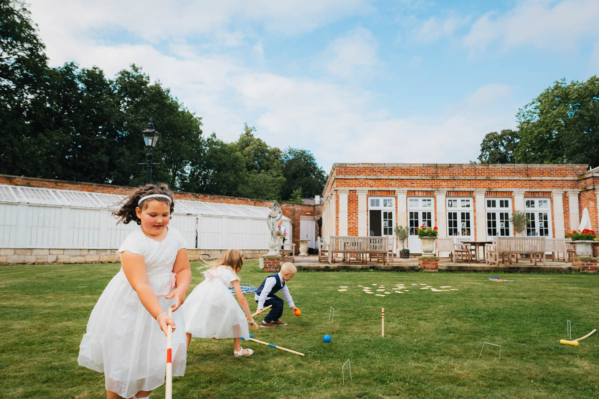 flower girls and pageboys play croquet on the lawn at the wedding venue
