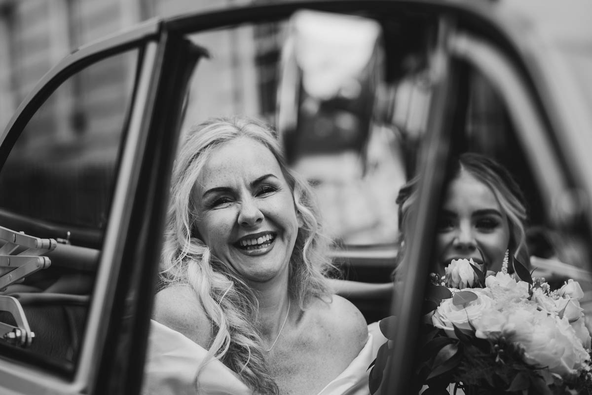 bride grins whilst being driven to her wedding ceremony