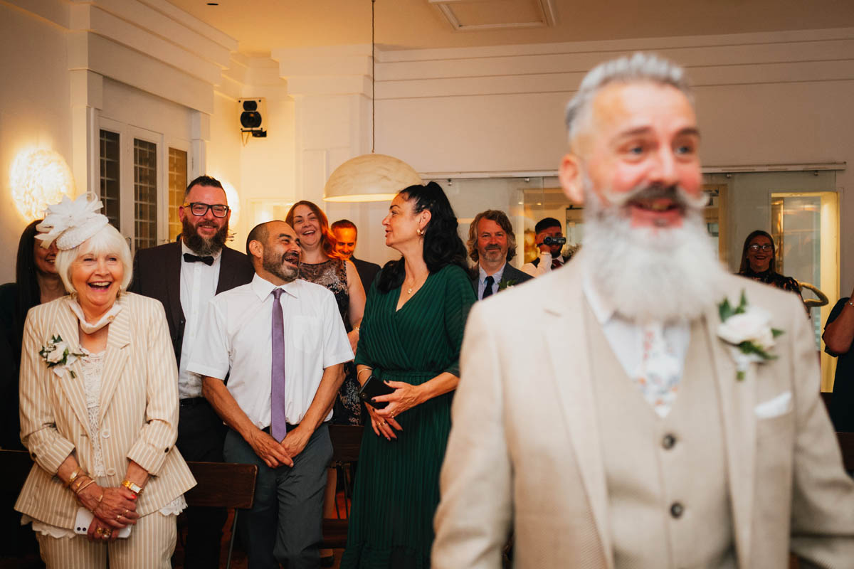 wedding guests laugh at the groom being funny