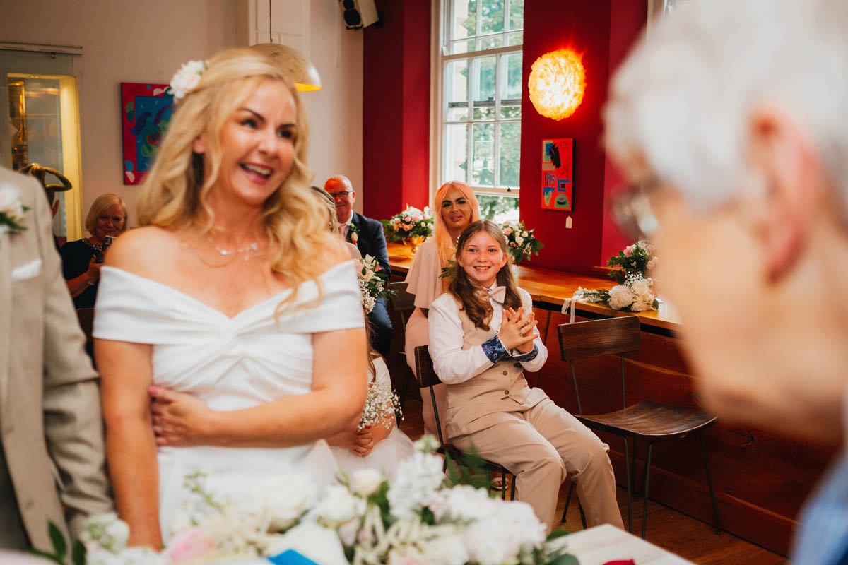 bride's daughter claps in delight as her mum ties the knot