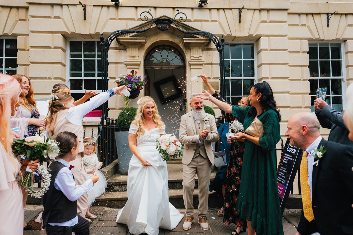 wedding guests throw confetti as the newly-weds exit the Berkeley Square hotel