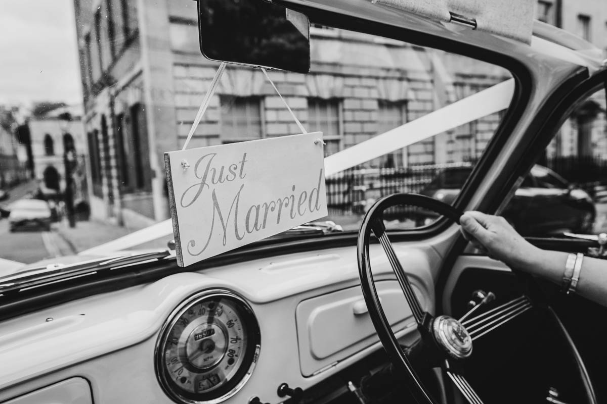 "just married" sign hanging on the wedding car mirror with Berkeley Square in the background