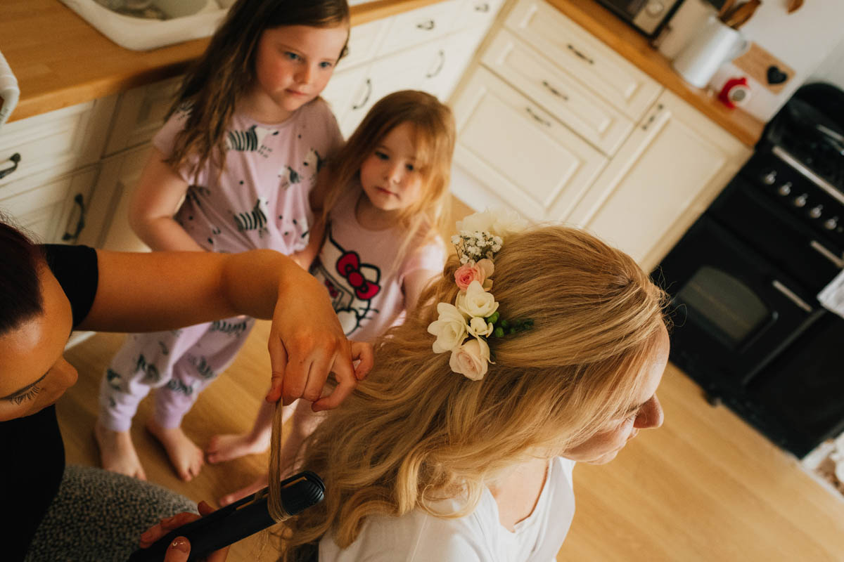 flower girls watch intently as bride has her hair curled for the wedding