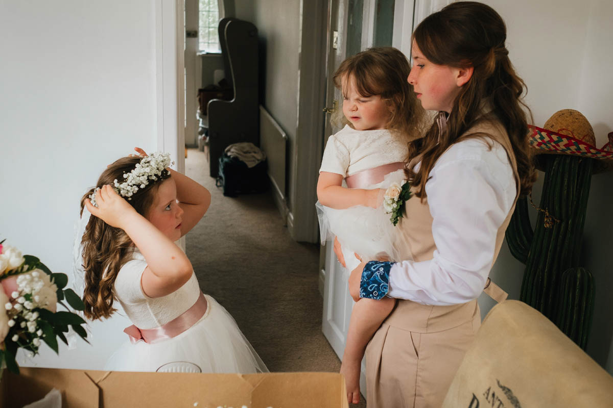 flower girl puts on her flower garland while bridesmaids assess