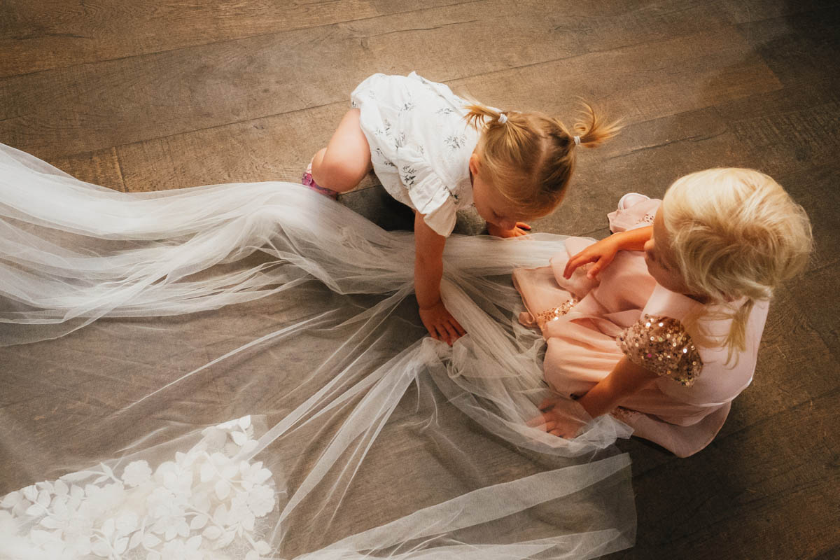 two little girls play with the bride's veil