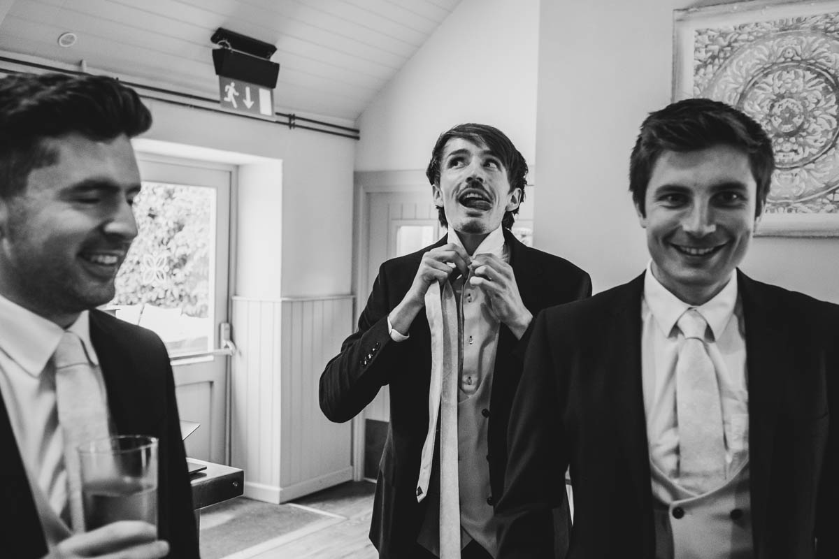 three groomsmen put on their ties
