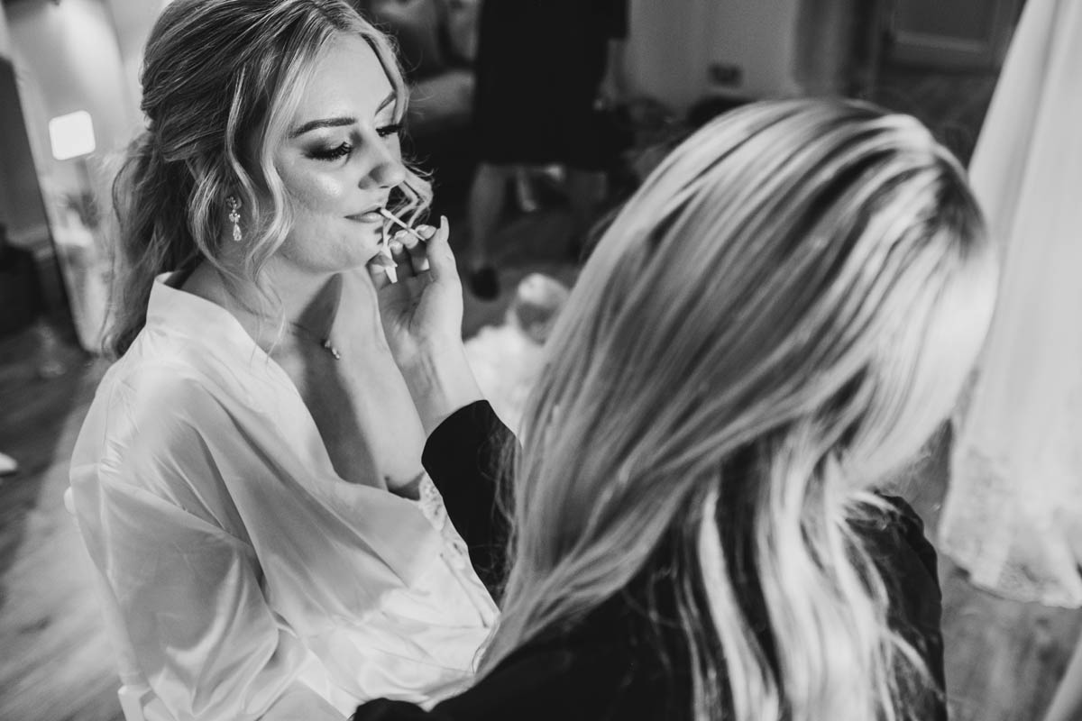 a make-up artist puts make up on the bride's lips
