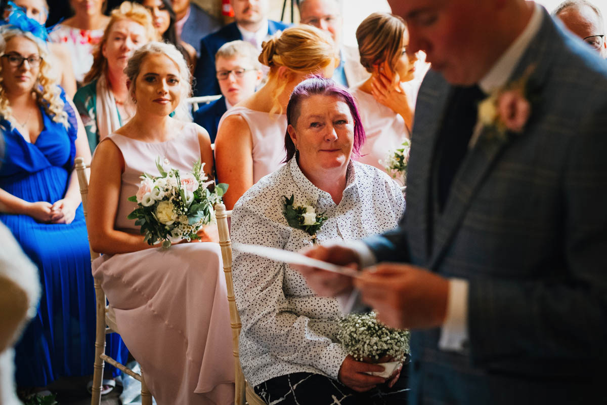mother of the groom looks emotional as the groom reads his wedding vows
