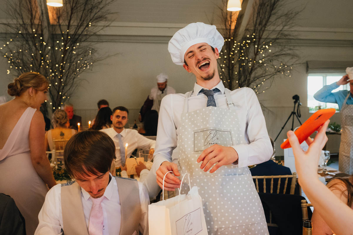 a wedding guests laughs as he puts on his chef hat, ready to carve the meat for the wedding breakfast