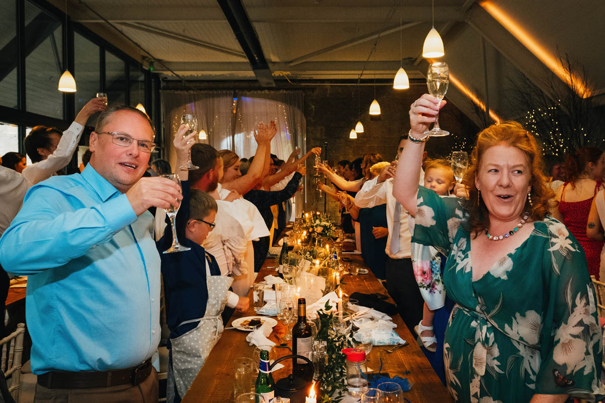 wedding guests raise their glasses as they toast the newly-weds