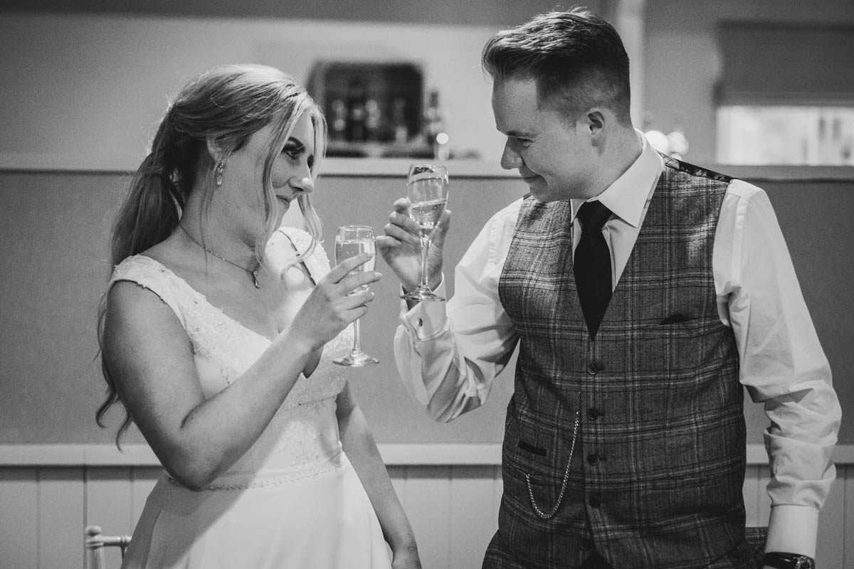 bride and groom tap their classes as they toast