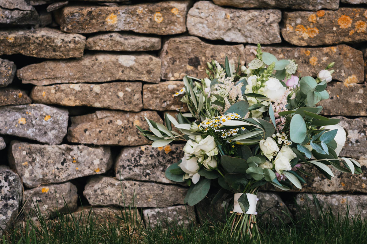 the bridal bouquet leaning up against a stone wall