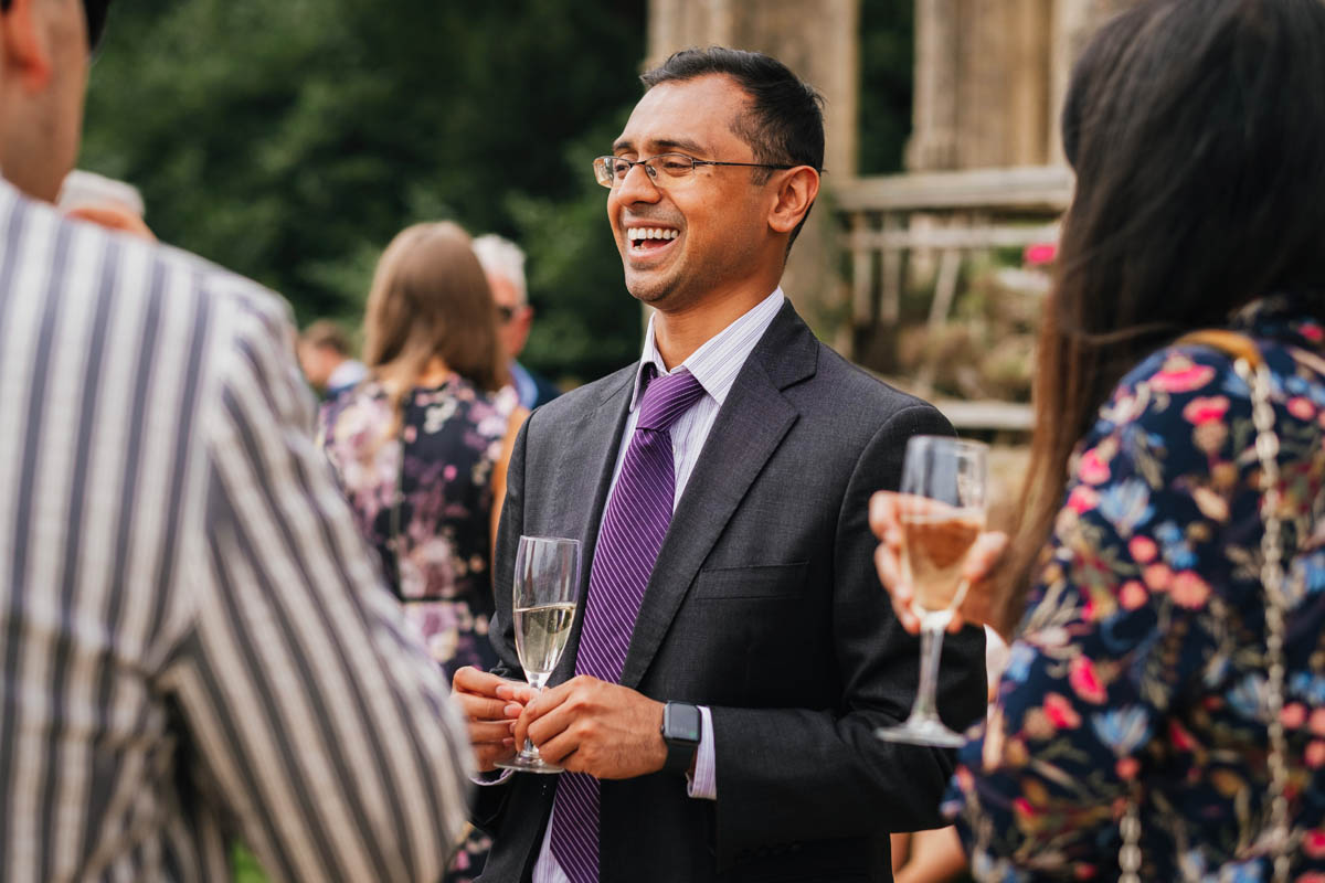 wedding guests drink champagne, laugh and chat during the drinks reception outside at Orchardleigh Estate