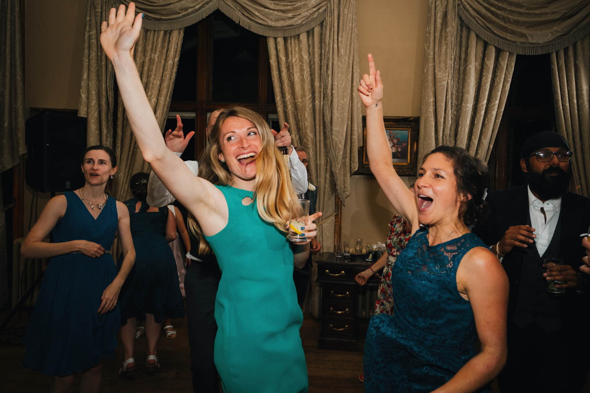 women throw their arms in their air on the dance floor