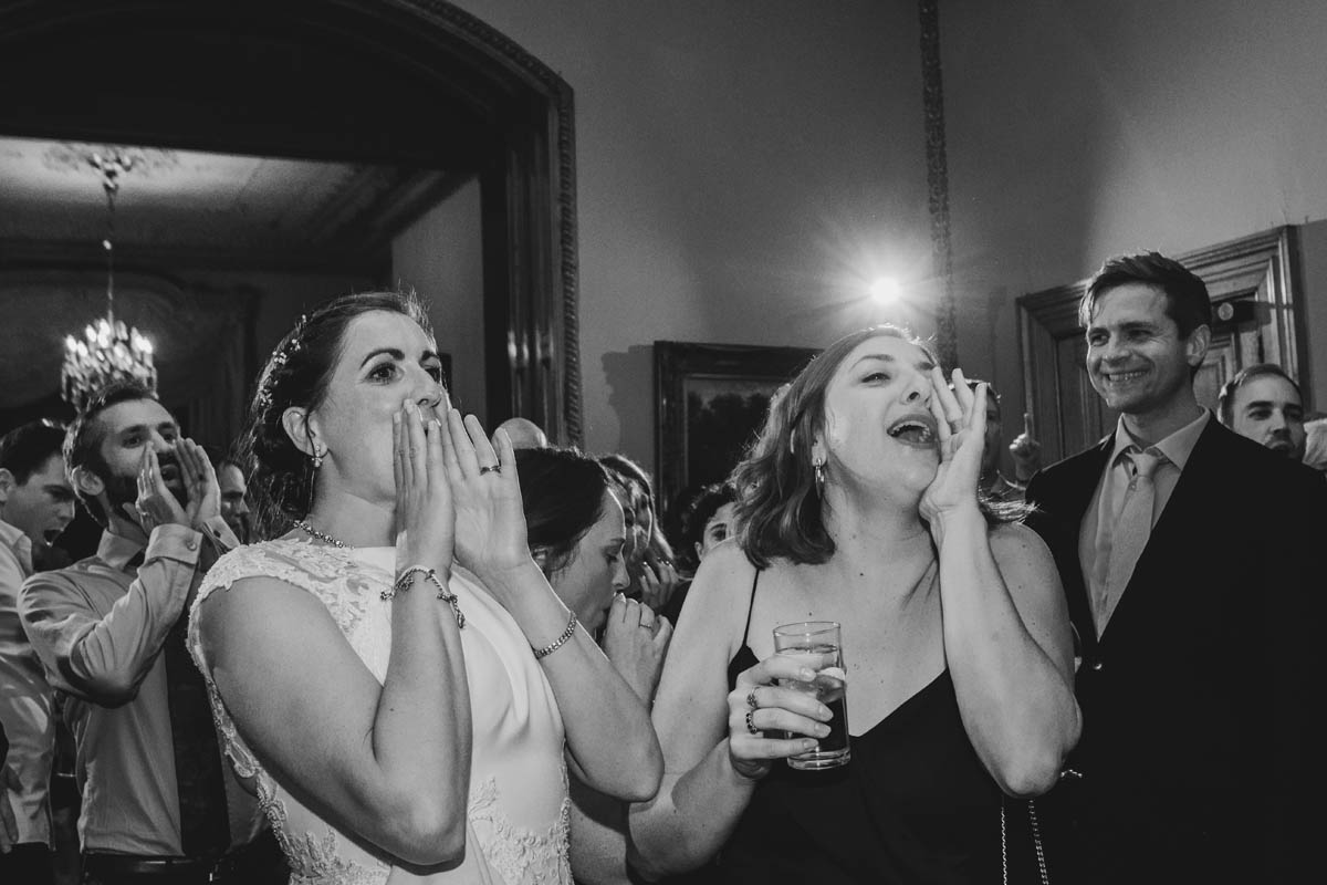 the bride and her friend shout while guests laugh behind at Orchardleigh House