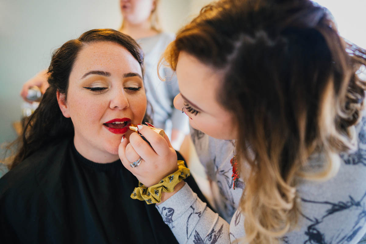 the bride's sister applies her red lipstick