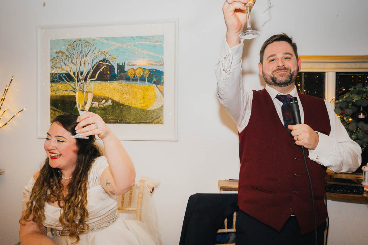 bride and groom lift their champagne glasses in a toast during the wedding speeches