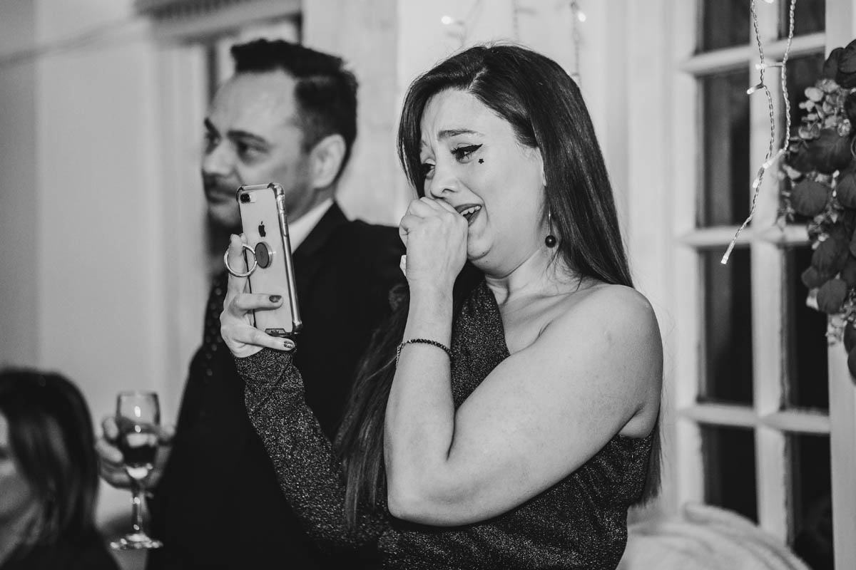 the bride's best friend cries and hold her phone up to record the wedding speech