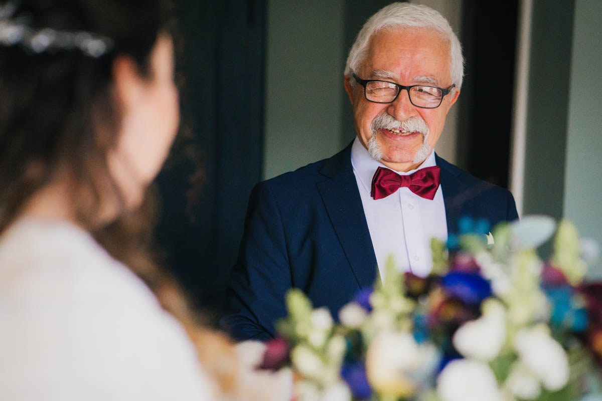 the father of the bride smiles at his daughter as he see's her for the firs time time in her wedding gown