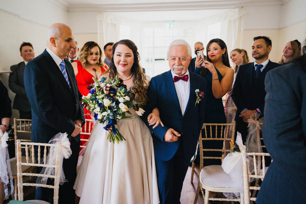 the bride is given away by her father as they walk up the aisle at her wedding ceremony
