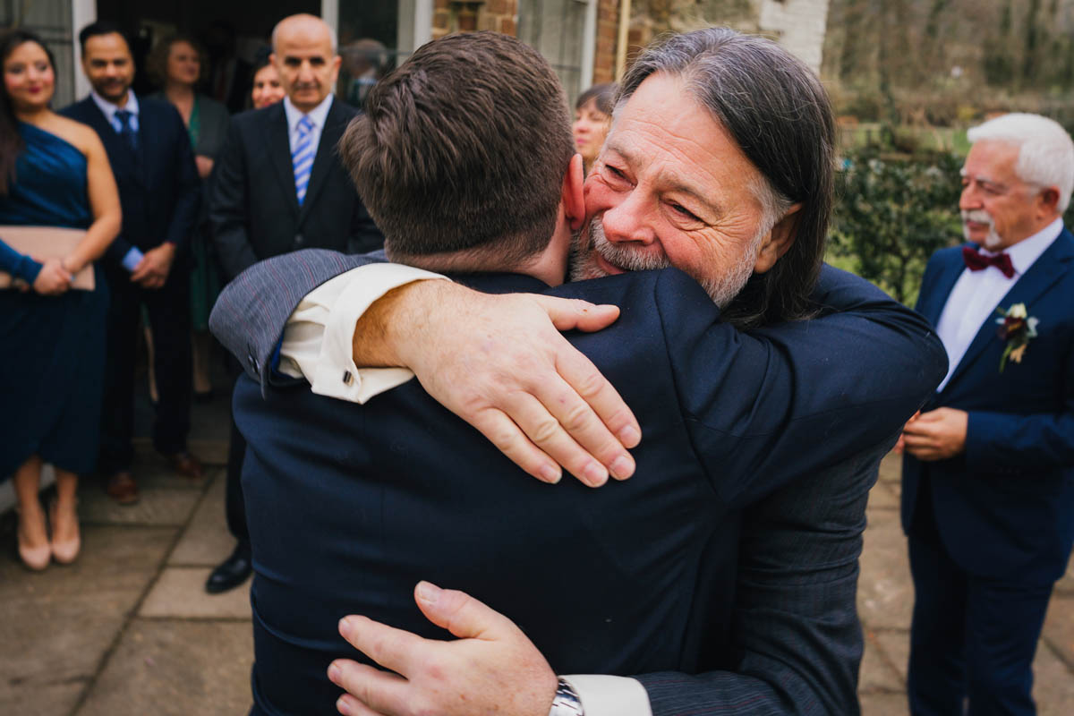 the groom's father hugs his son to congratulate him on his marriage