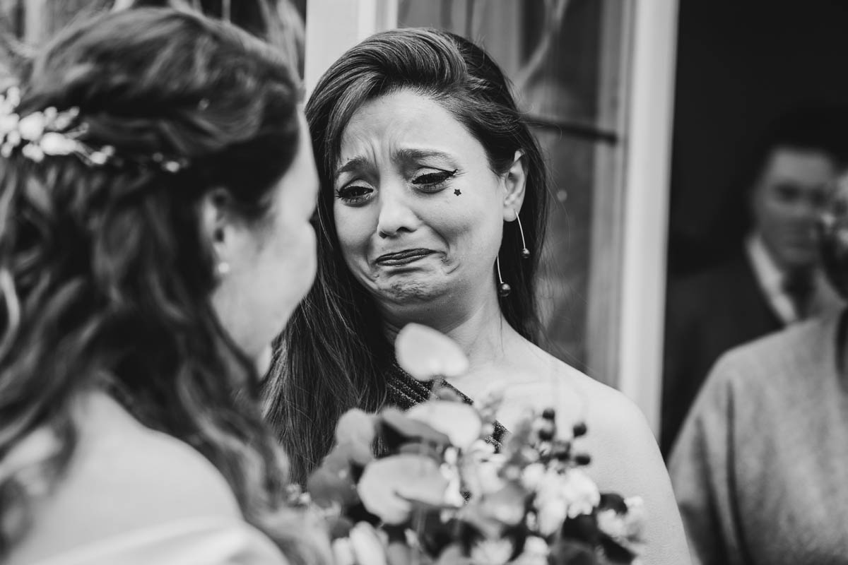 the bride's friend cries as she greets her just-married friend outside the ceremony