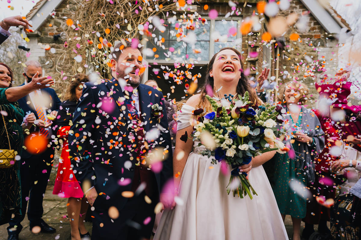 confetti covers the newly married couple while guests throw it in the background
