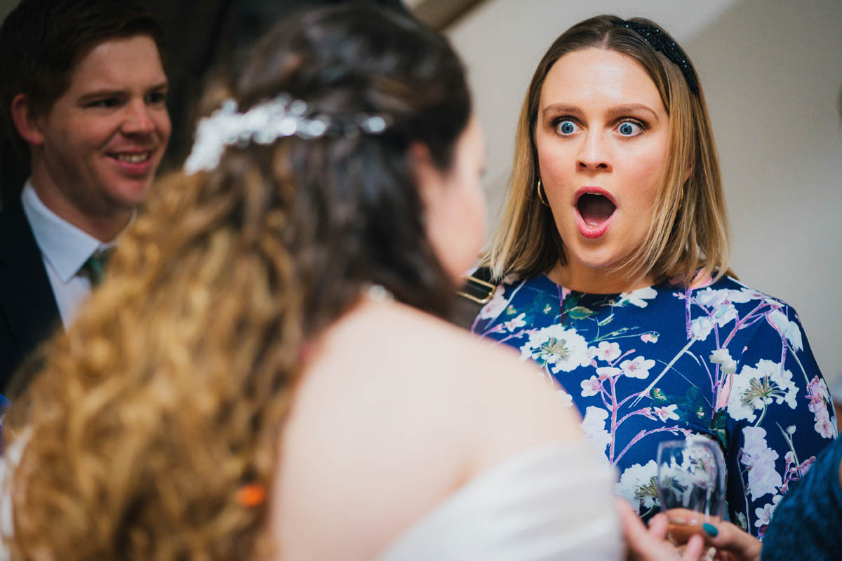 a wedding guests gasps with shock at the bride's story.