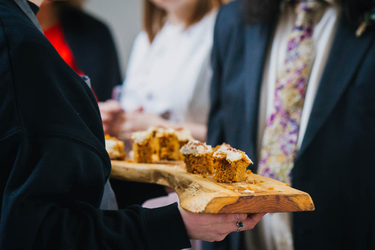 a close up of canapés being served to wedding guests on a wooden platter