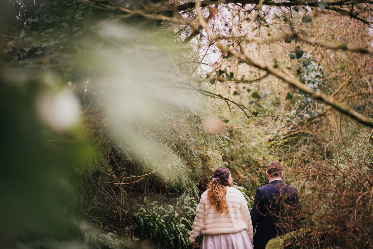 the groom and his bride walk through the woodland at springhead trust