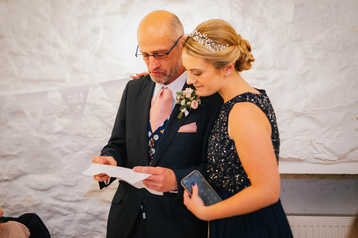 the bride's sister helps her father through the delivery of his speech