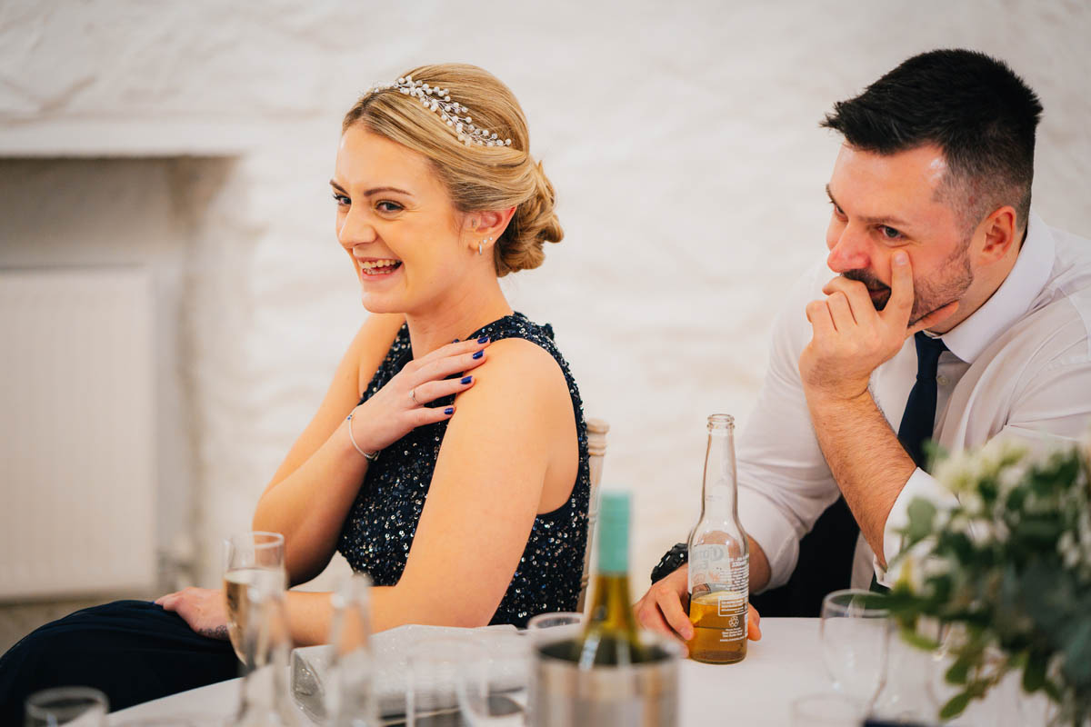 the bridesmaid and her fiancé laugh at the best man's speech
