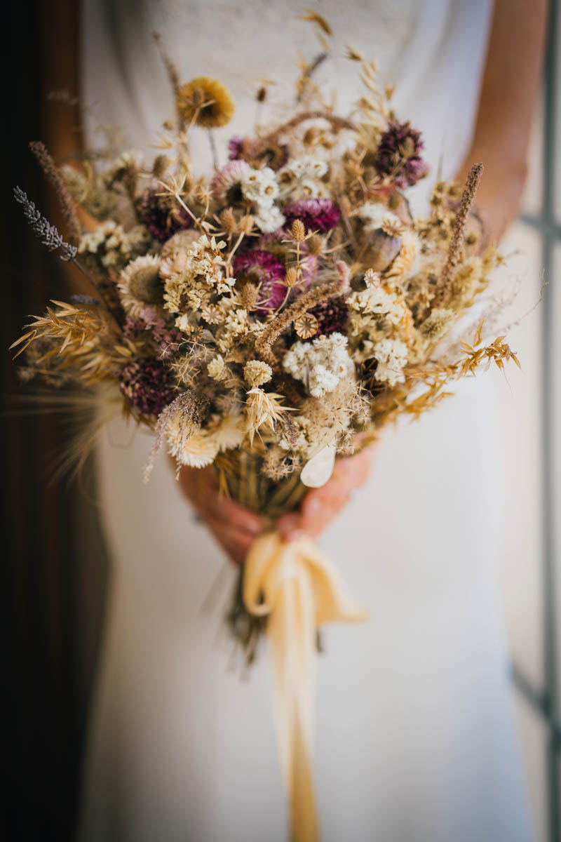 the bride's bouquet - a collection of dried wild flowers and a gold ribbon